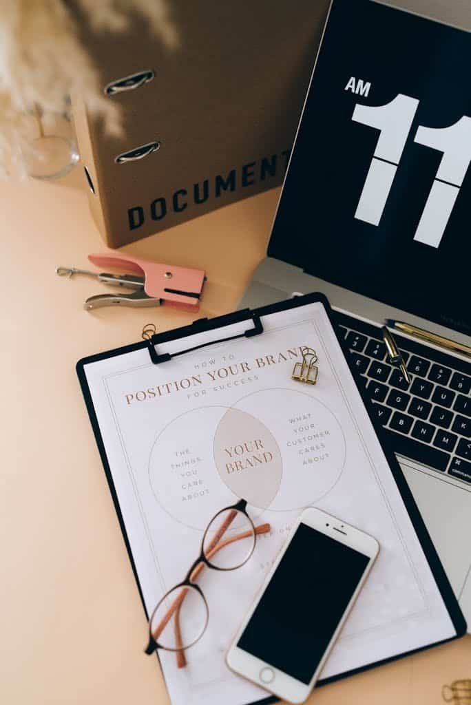Organized workspace with documents, laptop, smartphone, and glasses